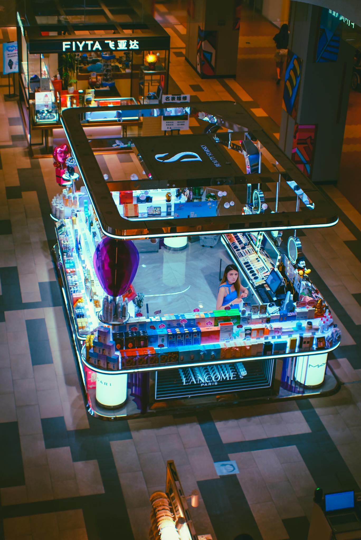 A vibrant view of a mall cosmetic kiosk showcasing products with a central salesperson.
