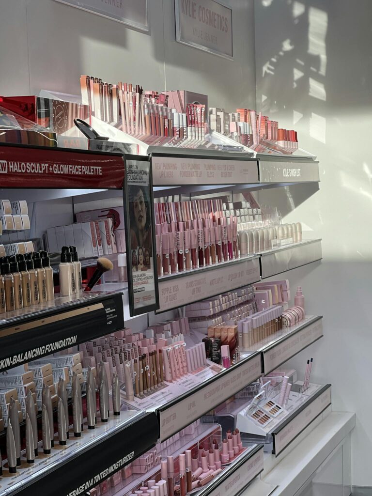 A well-organized makeup display in bright sunlight, showcasing various cosmetics on shelves.